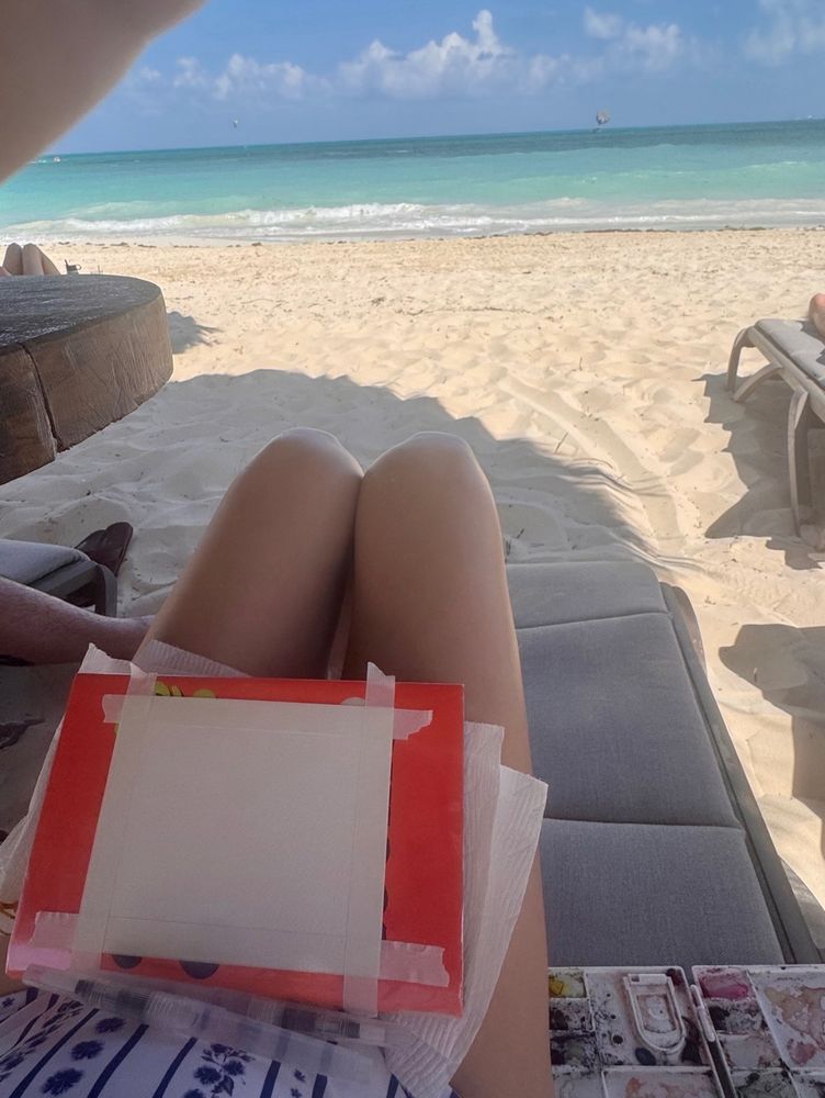 Painting setup in a beach chair in Playa Blanca, Mexico near Cancun. Watercolor paper taped to a book with a watercolor palette and two watercolor pens.