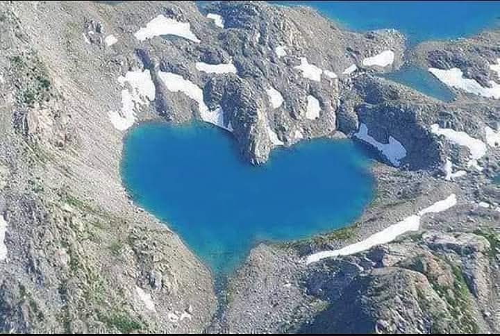 A heart shaped lake surrounded by mountains 