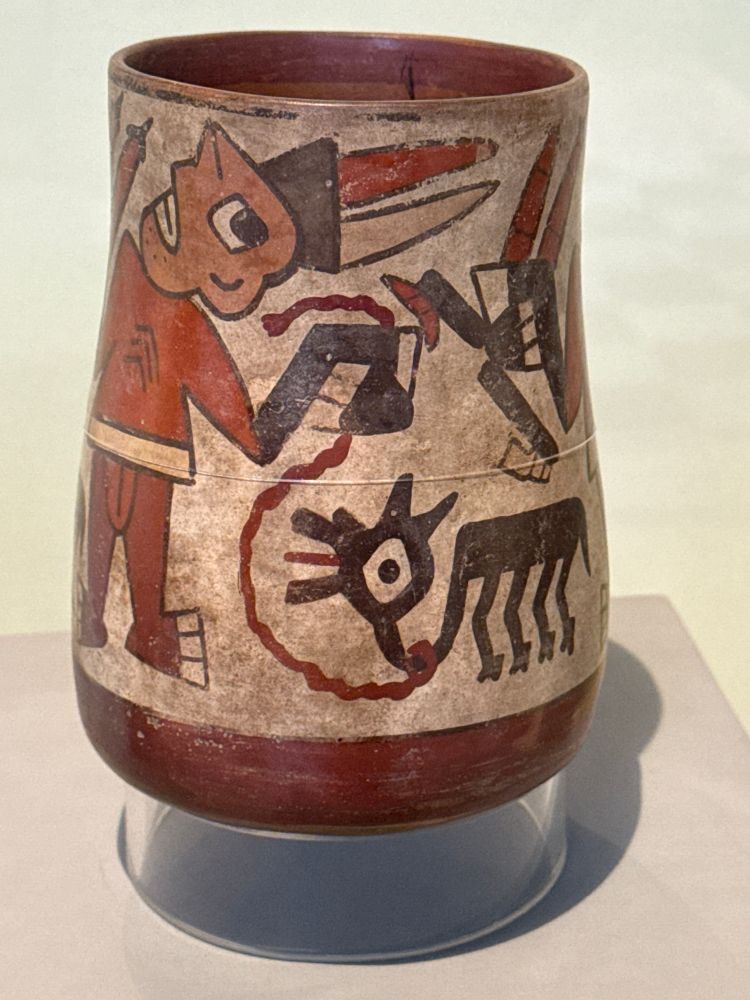 A grimacing figure painted on a cup , holding a leash that leads to a llama with its mouth open and tongue sticking out