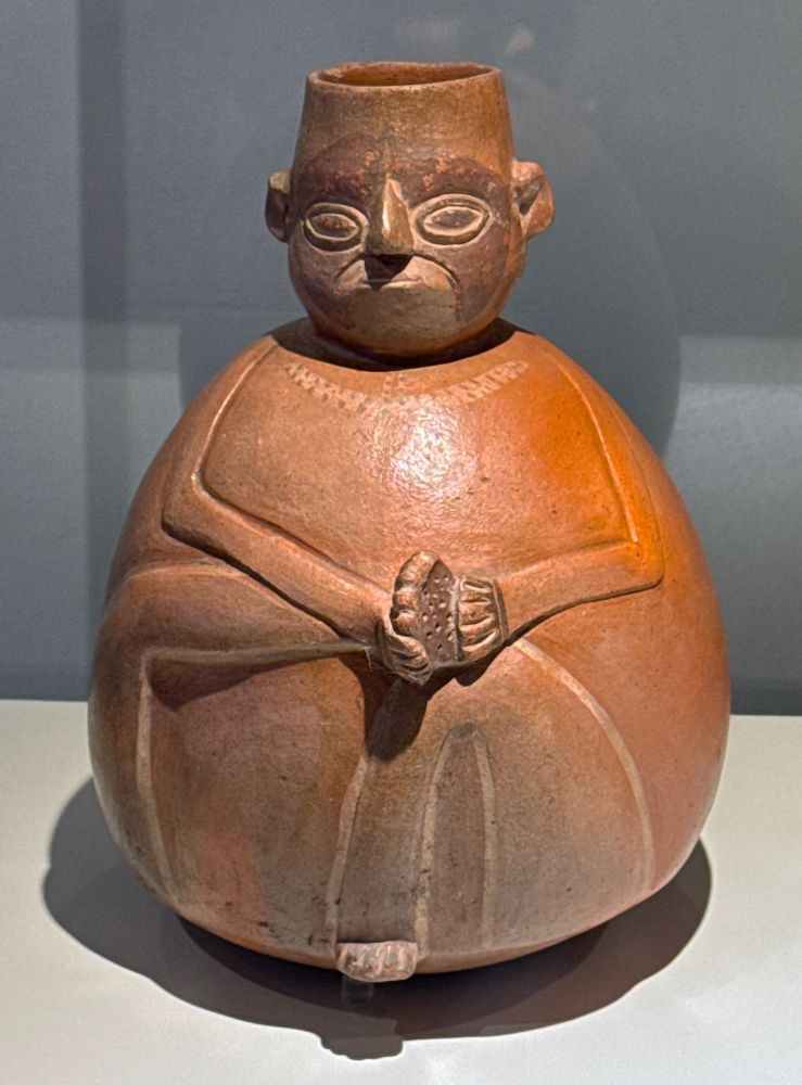 A pottery vessel with a man holding one foot up and scowling at it.