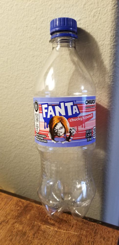 Picture of an empty Fanta soda pop bottle with a picture of an orange-haired doll (Chucky) and the words 
