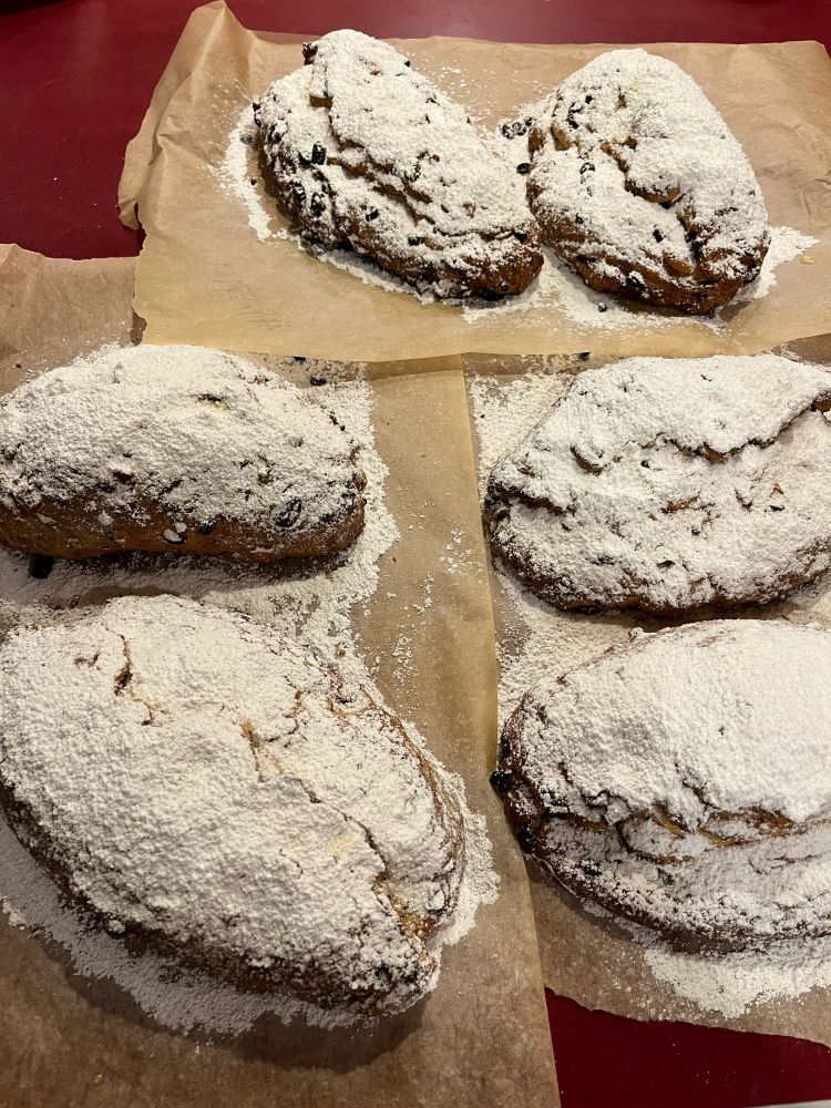Six freshly baked Stollen, dusted with powdered sugar.