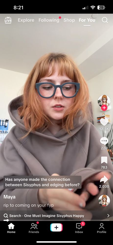 A tiktok screenshot of a young woman with red hair and a gray hoodie. The caption reads “Has anyone made the connection between Sisyphus and edging before?”
