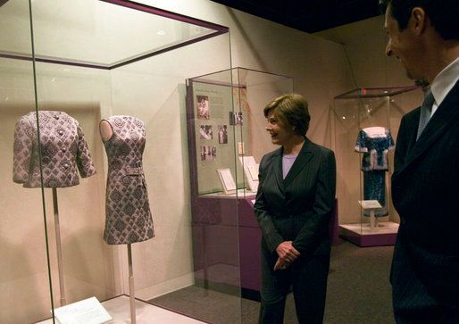 woman looking at a dress in a glass case