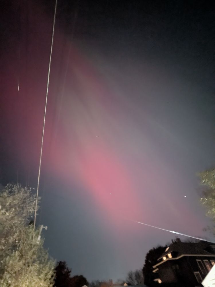 Big streaks of pink and green northern lights in the sky show in all four photos 