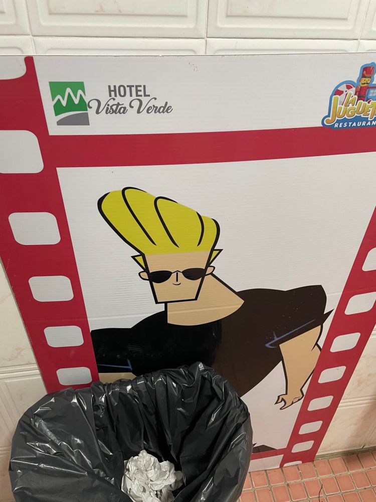A poster of Johnny Bravo by a trash can at a hotel in Puerto Rico