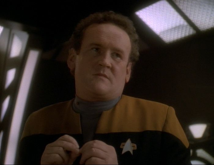 Chief O'Brien cocks his head with an annoyed expression while twiddling his fingers together.