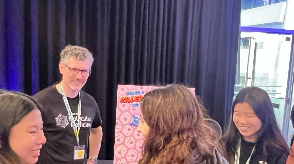 Dr Jesse standing next to the simulation of Killer T Cell sensing infected epithelial cells (on an art board next to him).