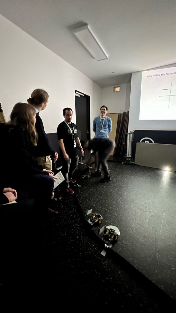 Dr Daryan, Guiyuan, and Matteo explaining and demonstrating the robots to a group of high school students.