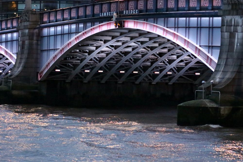 The central arch of Lambeth Bridge illuminated in pink and steel grey, part of a sequence of a light display along central London Thames bridges designed by Leo Villareal. To find out more, see: 
https://illuminatedriver.london