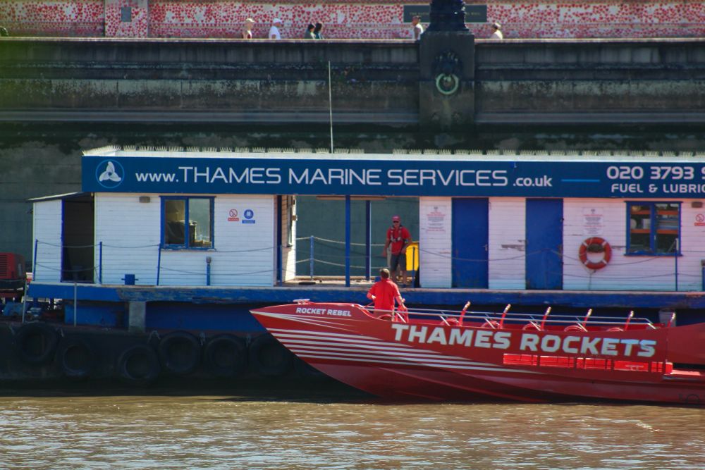 A red Thames Rocket RIB stops at the Thames Marine Services' r barge to refuel before setting out on her tourist trips.