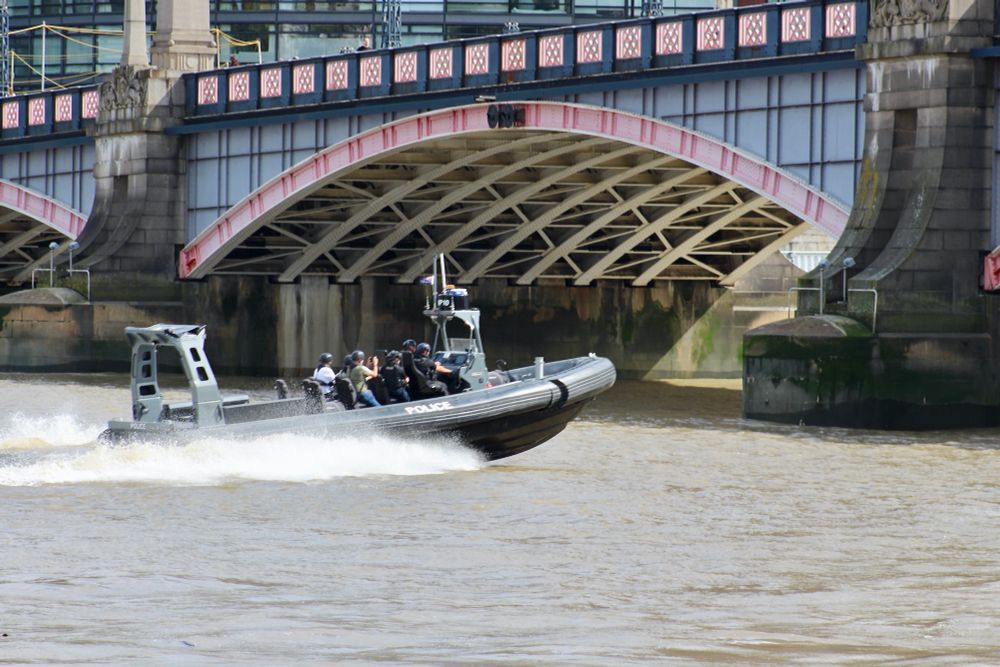 A black Thames Police RIB approaching Lambeth Bridge, making a splash as she heads upstream at speed.