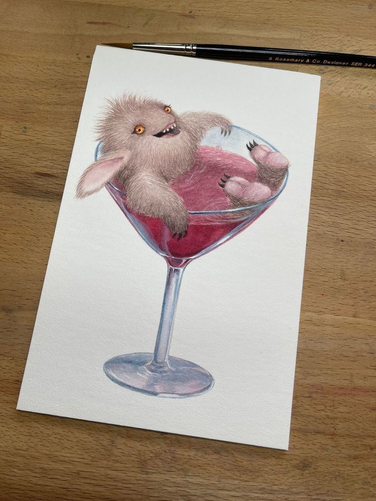 furry little brown monster bathing in a martini glass filled with a cosmopolitan cocktail. 