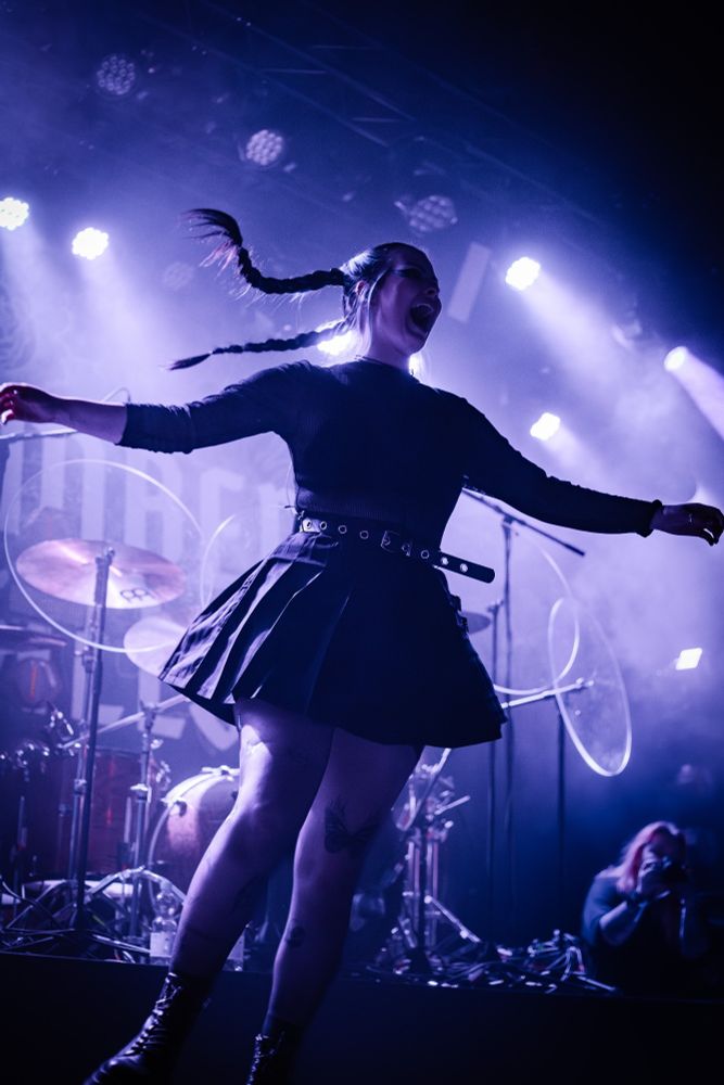 Singer of As December Falls swirling around on stage with her braids flying through the air