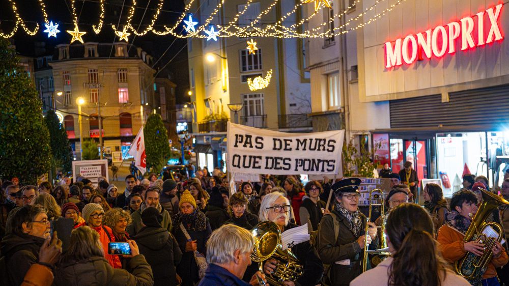 Manifestation à Limoges. Une banderole « Pas de murs que des ponts » est portée dans le cortège, accompagné d’un groupe de musicien·nes, entouré de manifestant·es.