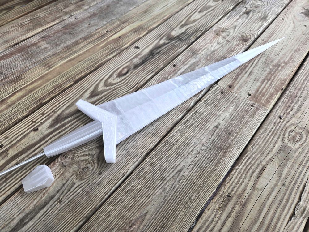 A translucent white sword with a triangular blade. An aluminum rod runs through the blade, guard, and grip. The long hexagonal pommel is to the side since the rod is too long.