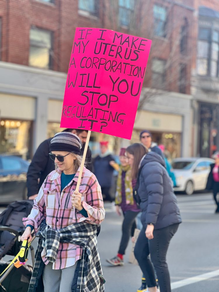 A woman holding a sign that says "If I make my uterus a corporation will you stop regulating it?"