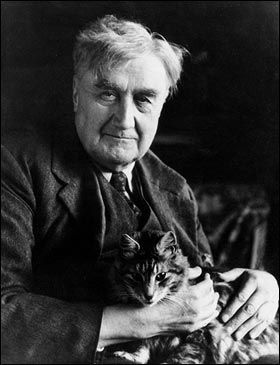Black and white photograph of Vaughan Williams as an older man, holding his cat. He is wearing a suit and tie.