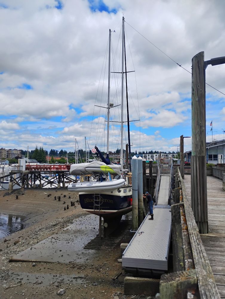 A Nauticat 44 is docked at the Olympia Yacht Club on a pleasant summer day.

The sky is blue with some high, puffy clouds.

The sailboat owner is working on the engine and making other repairs during one of the year's lowest tides.

The boat is named Blue Heron. Fitting for Olympia. There is a heron rookery directly across Budd Inlet from the OYC.

In all my decades of boating and spending time on the Puget Sound waterfront, I had never seen a boat drydocked in that location.

There is a large metal plate installed on the shore of Budd Inlet. The boat was resting on that while the owner made his repairs.

He sailed away when high tide returned.

Very Cool. ⛵
