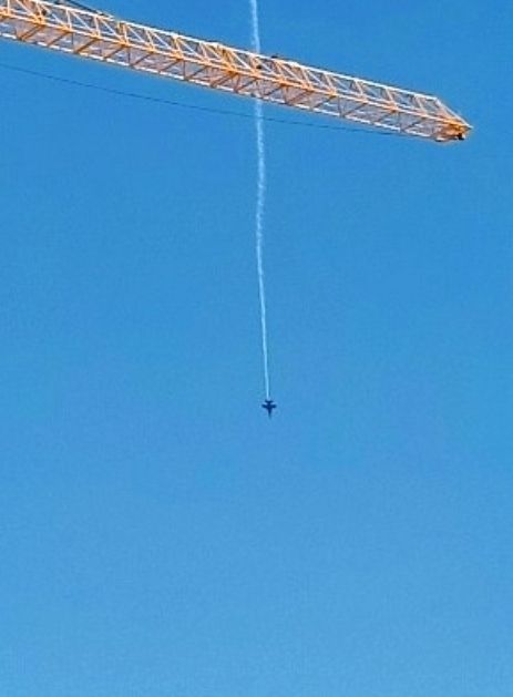 A blue-sky day in Seattle.
August of 2024.

A Navy jet dives straight down above the Emerald City skyline.

The Blue Angels fly Boeing F/A-18 Super Hornets.

They perform annually for Seafair, a summer festival in the Pacific Northwest.

Description:

A yellow industrial crane.at the top of the frame.

A Blue Angel in the middle of the frame.

A white contrail behind the diving jet.

A beautiful day on the Elliott Bay waterfront.