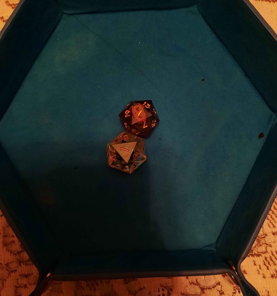 two 20-sided die in a dice tray, both with a “1” showing. 