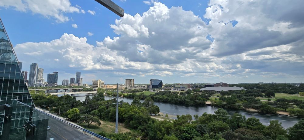 View of trees, clouds and buildings from the top floor of the Austin public library. 