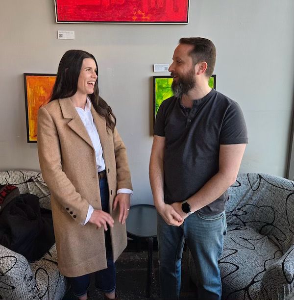 Emma Harrison standing with Andrew MacGregor having a conversation in front of paintings