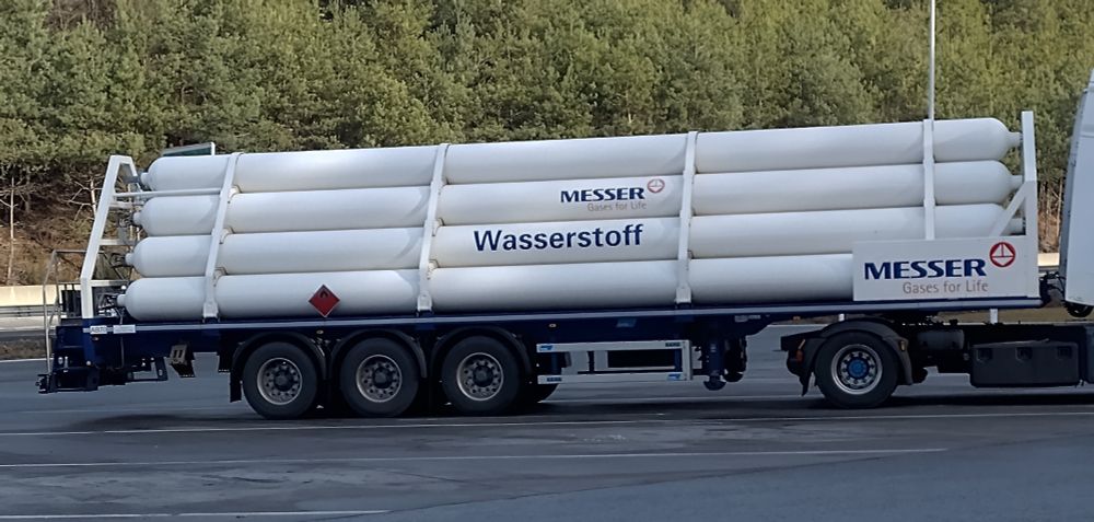 Seitenansicht eines LKW-Auflegers der mit zehn weiße Wasserstofftanks beladen ist