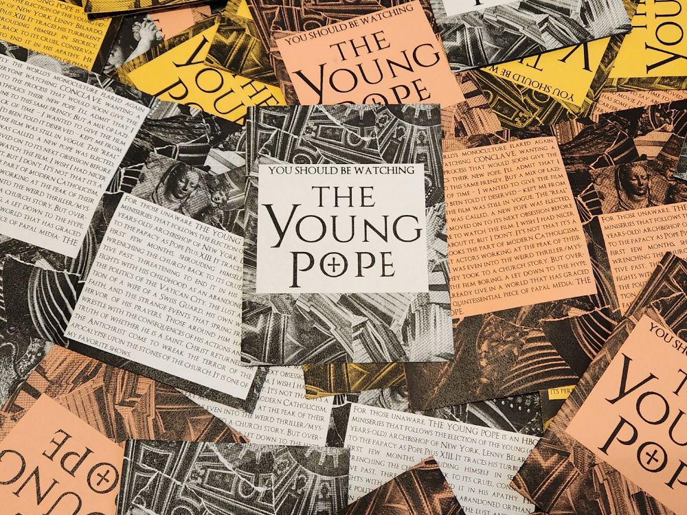 A number of copies of "You Should Be Watching The Young Pope" laid on top of one another, printed in red, white, and yellow.