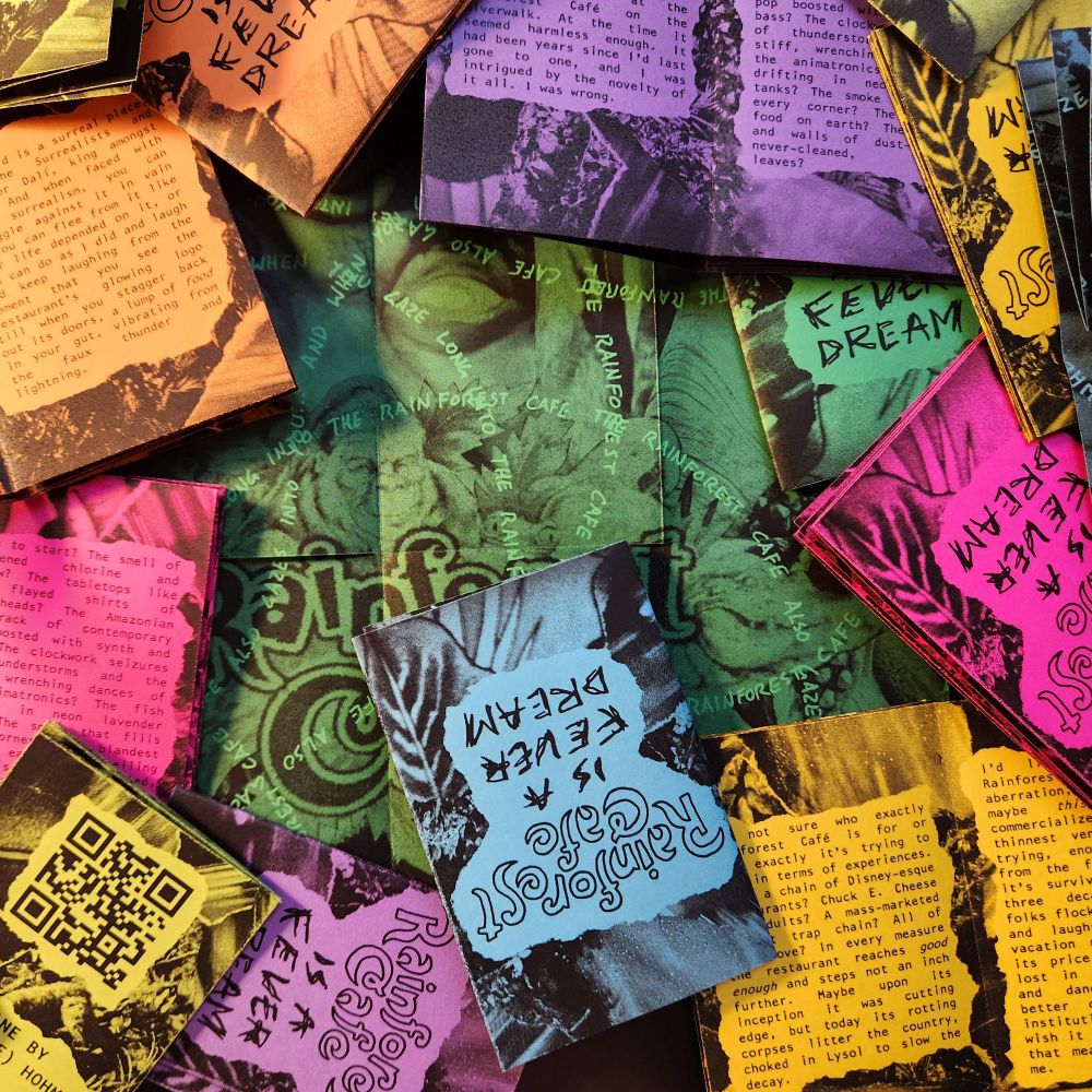 A stack of rainbow-colored zines titled "Rainforest Cafe is a Fever Dream," featuring their back covers and insides.