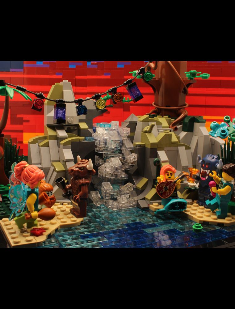 a lego built lagoon with magical creature minifigs on the beach and a waterfall in the middle