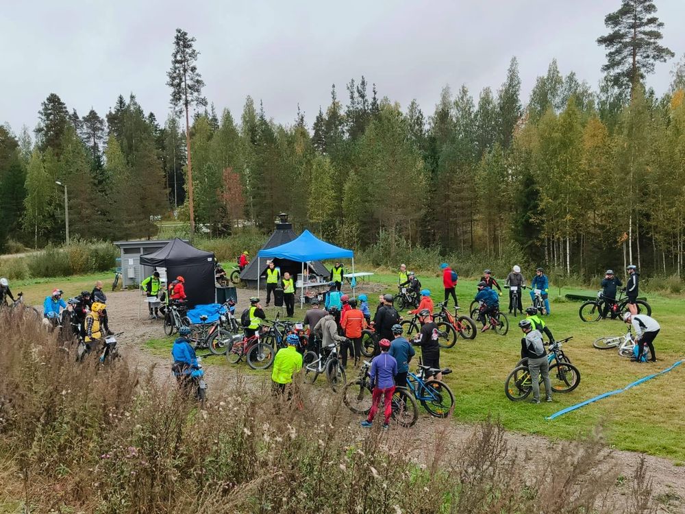 Kuhinaa ennen lähtöä. Pyöräilijät kuuntelee infoa kentällä.