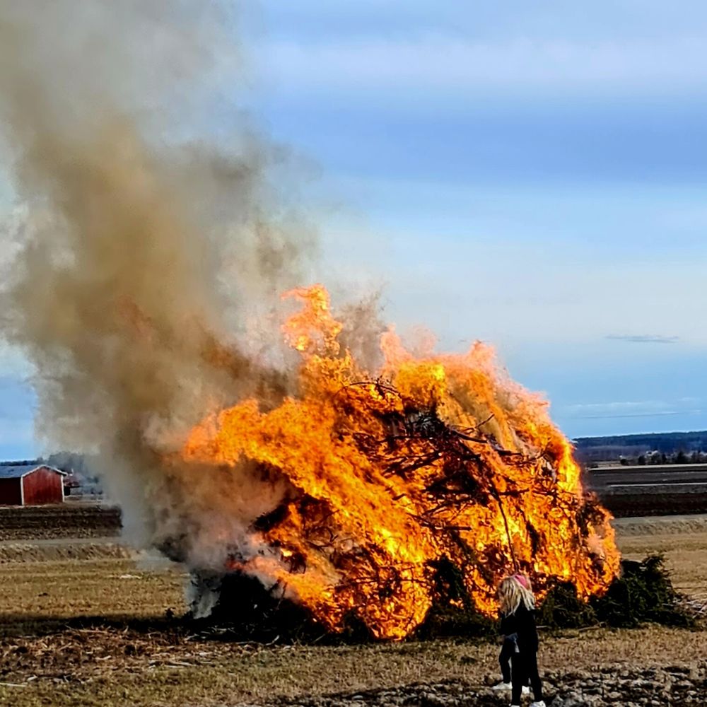 Pääsiäiskokko tulessa pellolla. Taustalla lato ja aava.