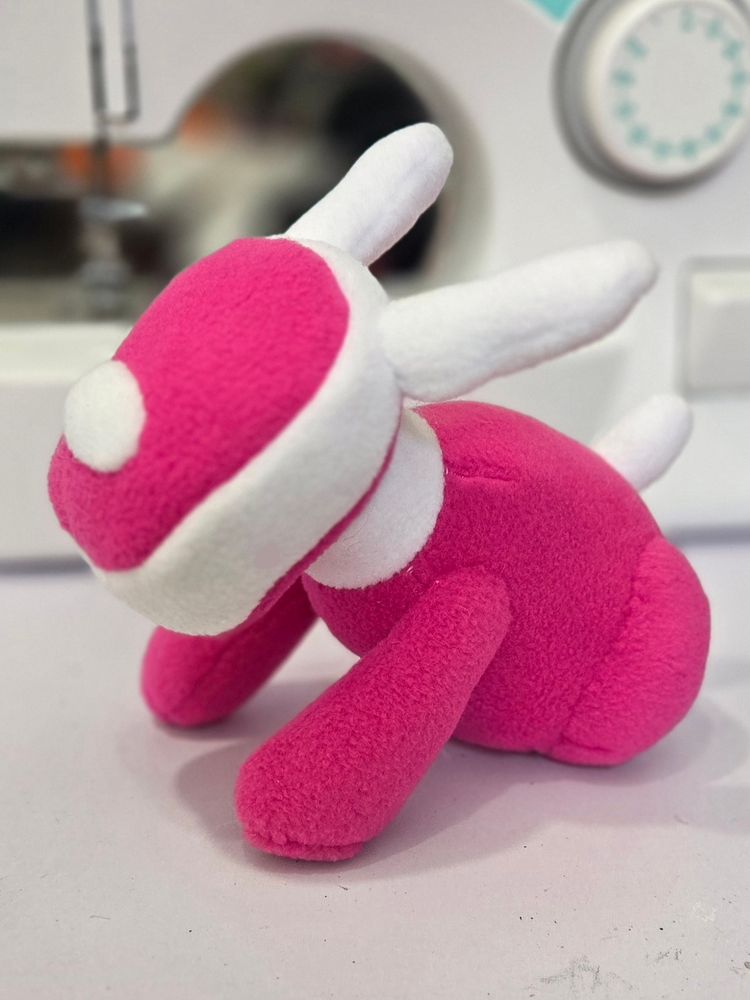 A photograph of a pink and white iDog plushie.