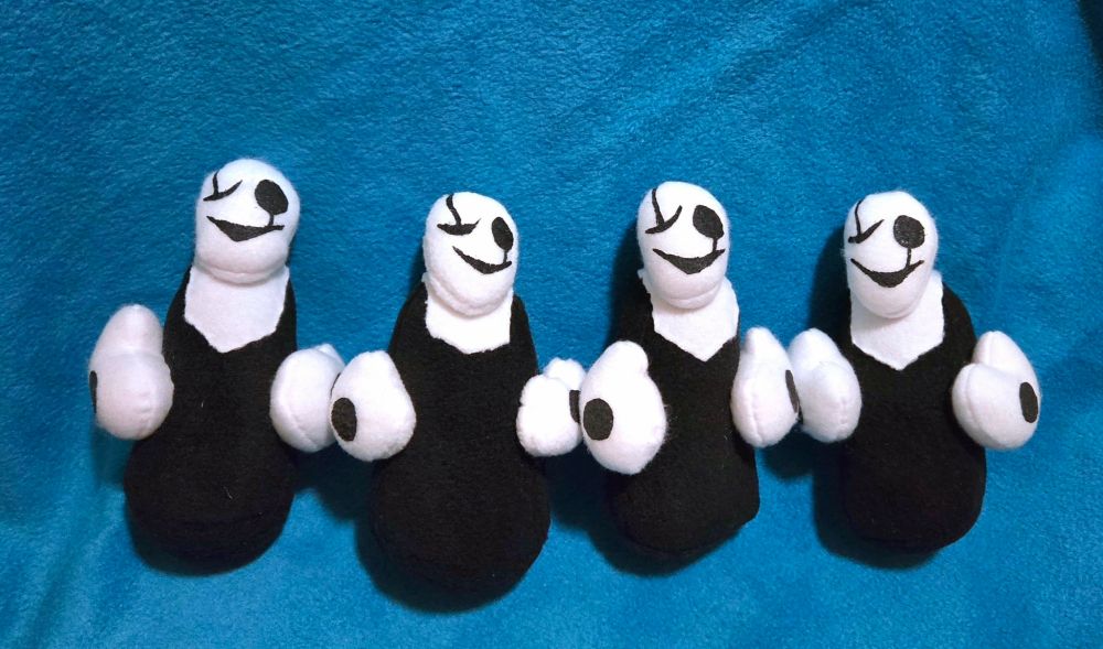 A photograph of four handmade W.D. Gaster plushies lined up on a blue background, replicating the Buddy Holly album cover by Weezer.