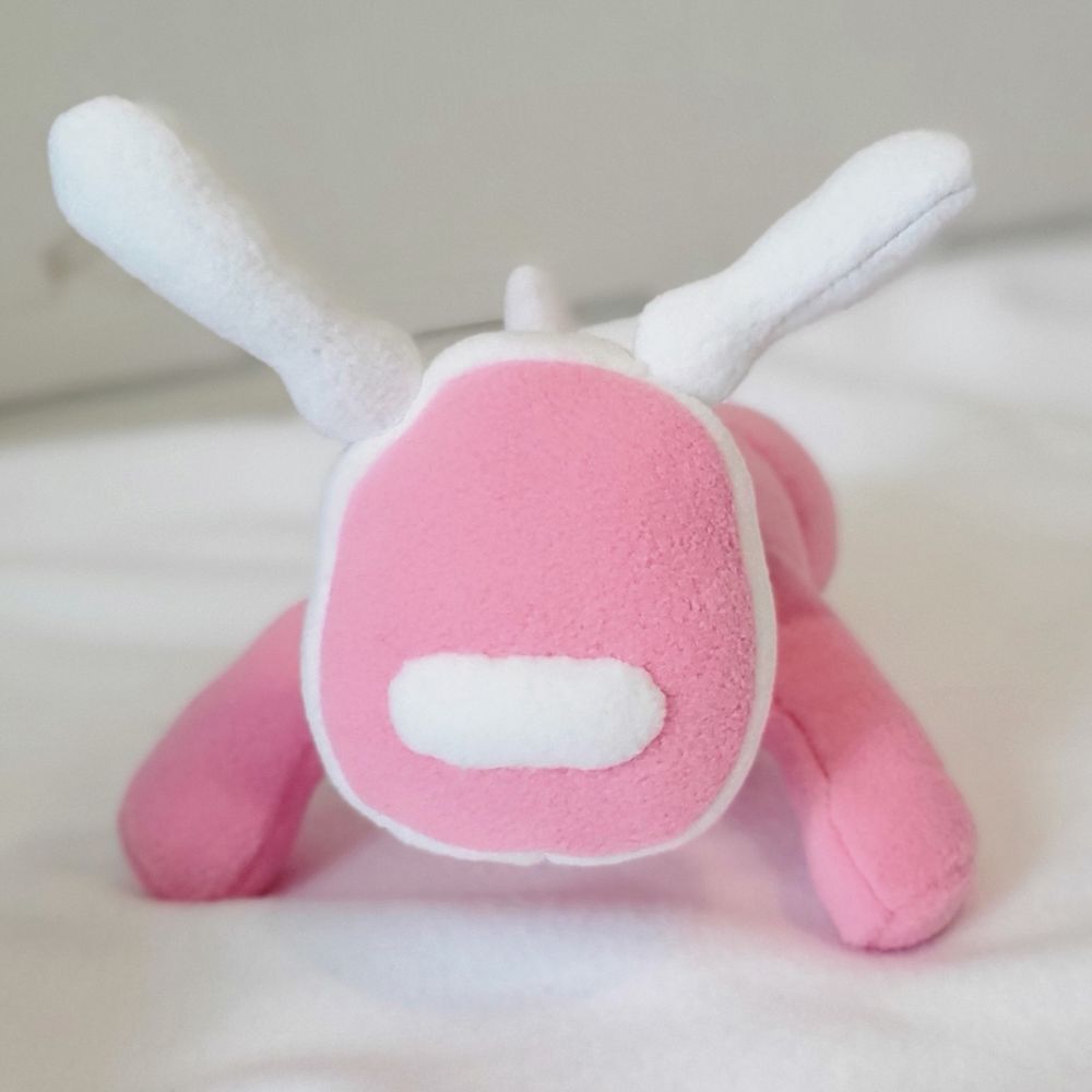 A photograph of a pastel pink iDog inspired robot dog plush toy. It has white accents.