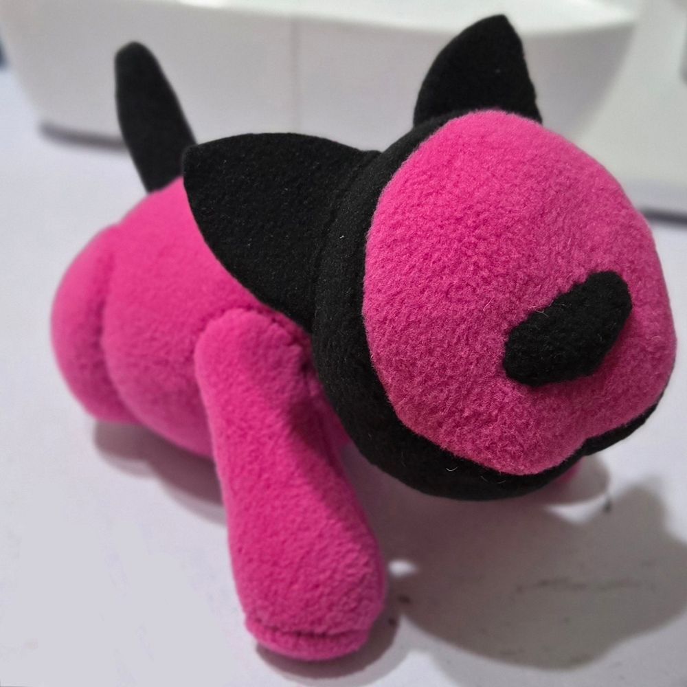 A photograph of a bright pink iCat inspired robot cat plushie. It has black accents.