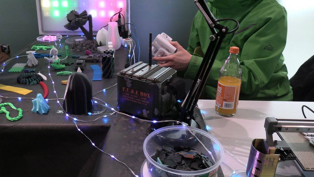 Blick auf einen Teil des Haxko-Stands. Links hinten: Pixeluhr, davor diverse 3D-Drucke. Cyberdeck "F.U.S.E BOX" in alten Militär-Ersatzteilkasten und 3D-Drucker