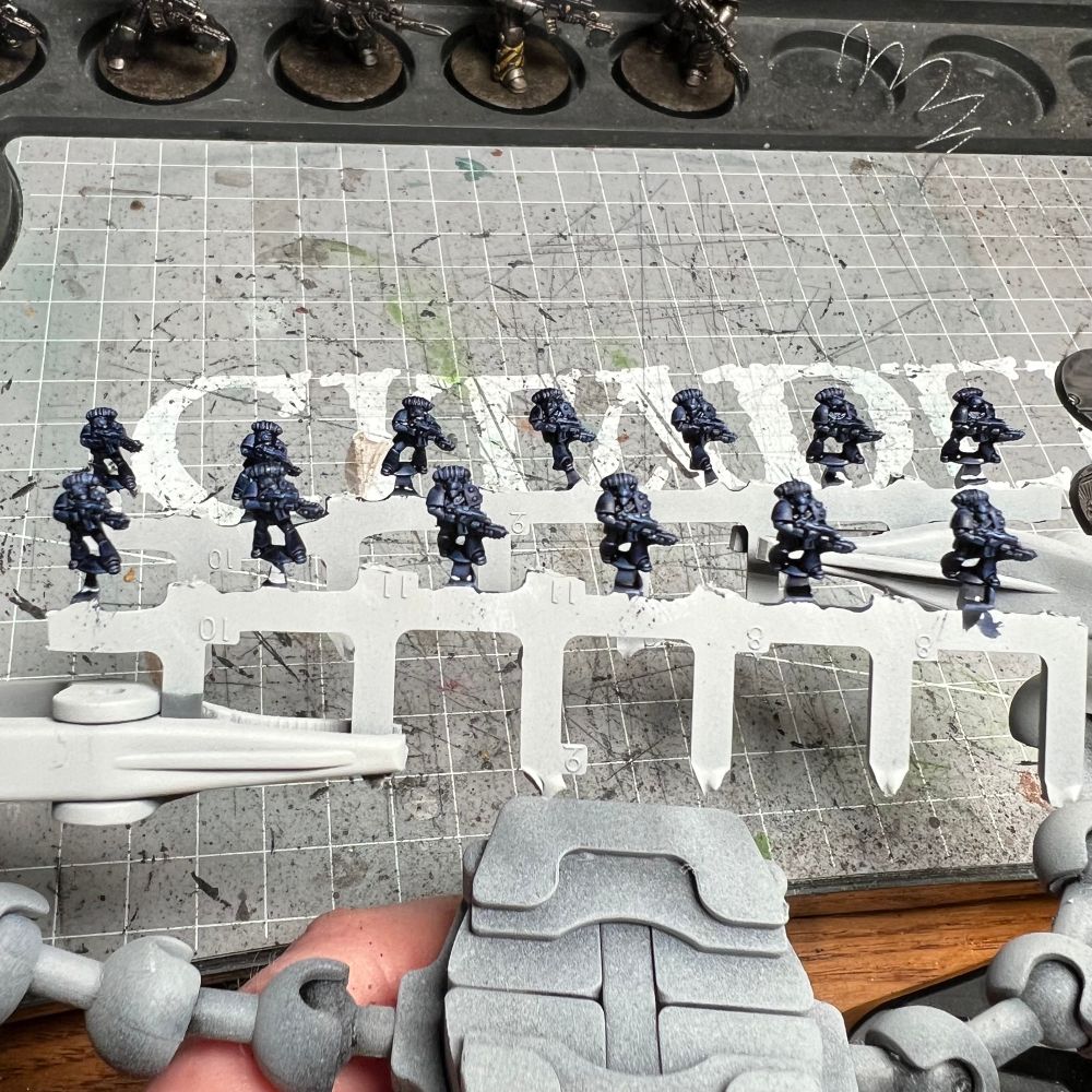 13 6mm tactical marines, still attached to sprue, painted in dark blue
