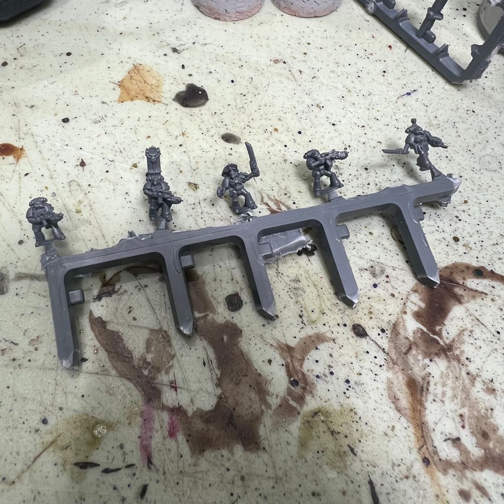 5 6mm space marines attached to a long piece of plastic sprue