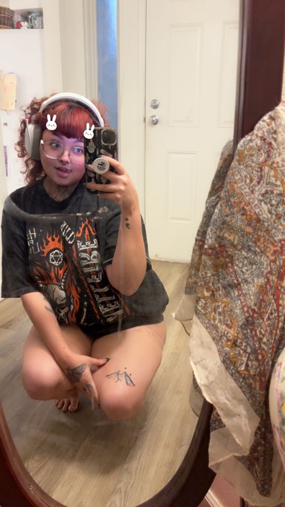 kura crouching in a mirror wearing a big tshirt and her headphones 