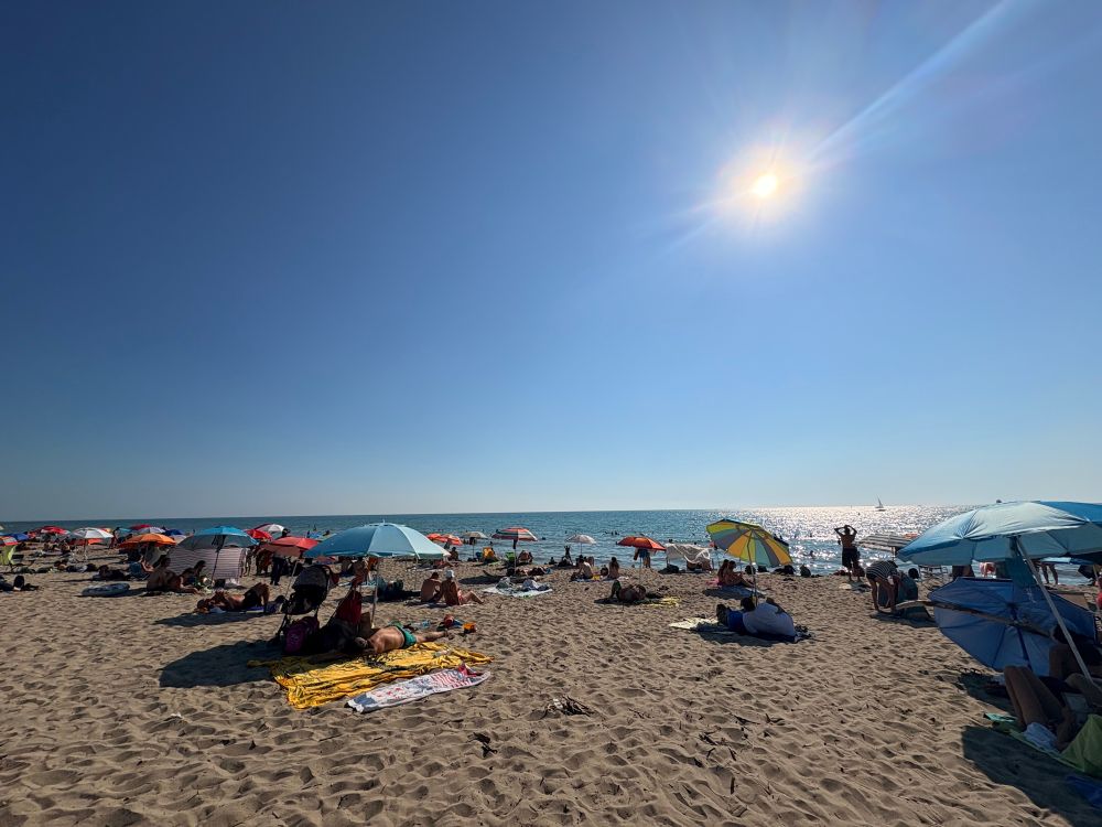 Plage de sable fin, le soleil ardent sur les baigneurs. 