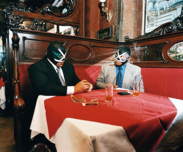 A photo of two guys in luchador masks and suits and ties, sitting at a table in an old fancy restaurant, drinking and smoking. I got this from Pinterest, and I don't know more about it than that.