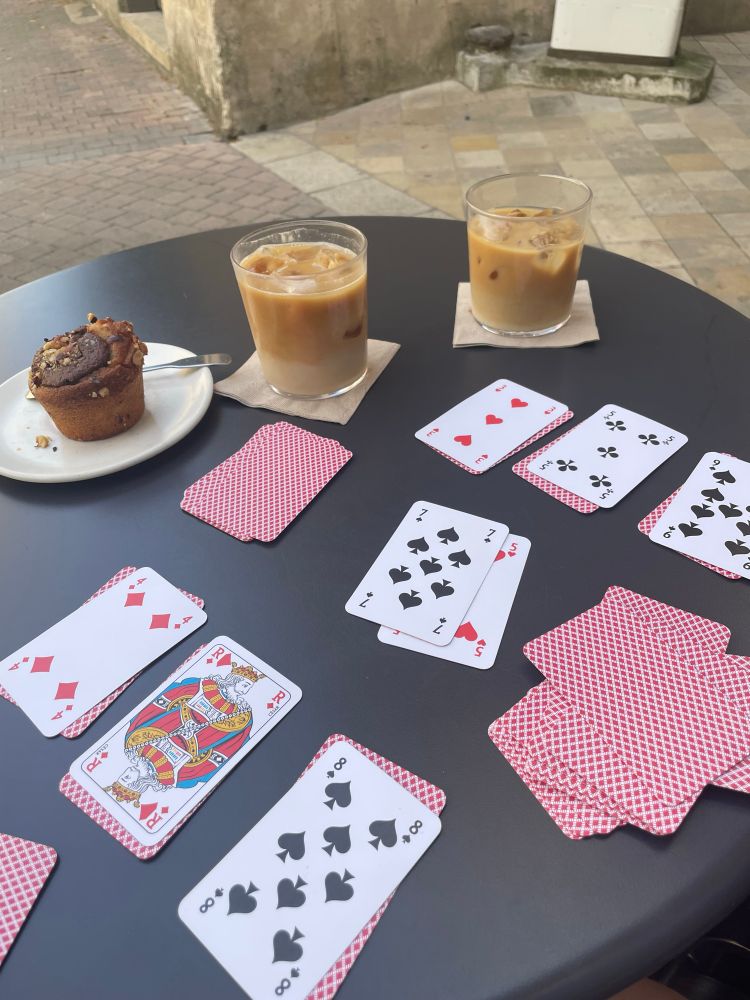 Table en terrasse avec deux cafés latte glacés au lait d'avoine et un financier. Il y a une partie de clémentin en cours entre Zoe et moi. 
