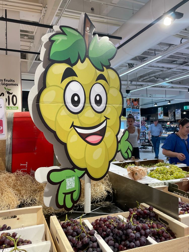 Maxi pancarte d'une grappe de raisin goofy dans un supermarché.