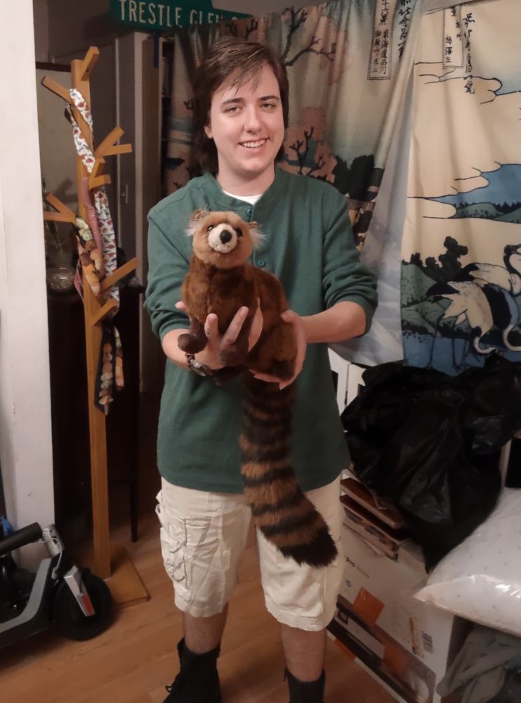 Photo of someone dressed as Chris Kratt from the Kratt Brothers, holding out a plush mongoose.