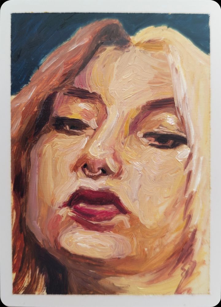 A painting of a person with split-coloured hair, half red, half blonde. They are looking down on the viewer in a curious manner. They have a nose ring, and full lips. The main colours are reds, pinks, and yellows, in front of a dark blue background.