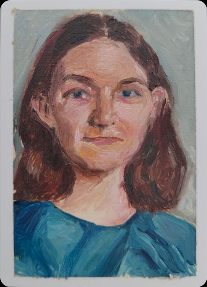 A painting of a person in a blue top in front of a sage green background. They are half-smiling, and their brown hair is shoulder length.