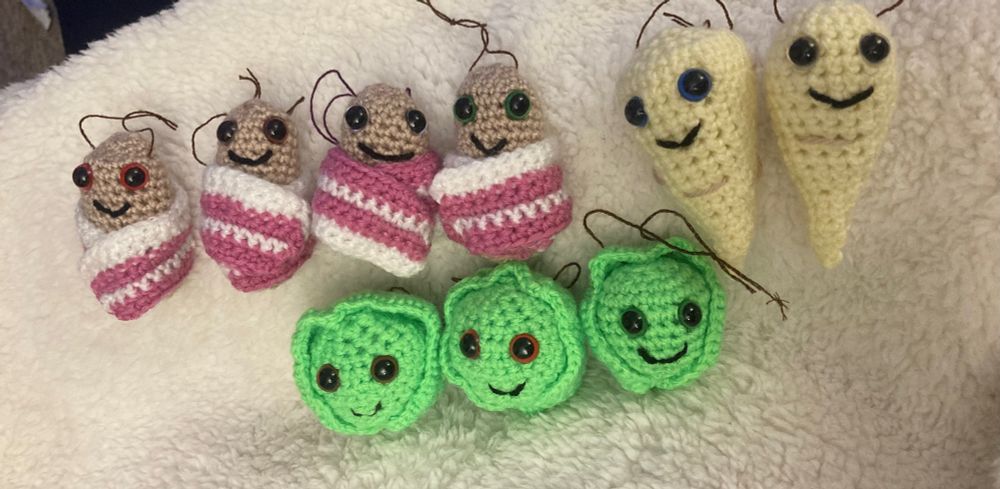 A row of slightly untidily crocheted Christmas pigs in blankets, parsnips and Brussels sprouts.