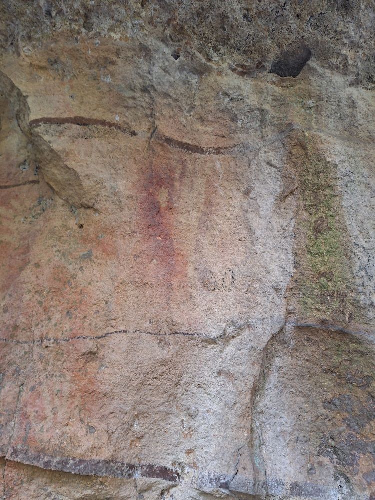An outline of a hand left by spitting red ochre at a sandstone cave wall